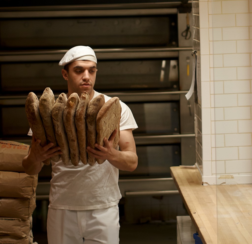Baker carries bread from oven.