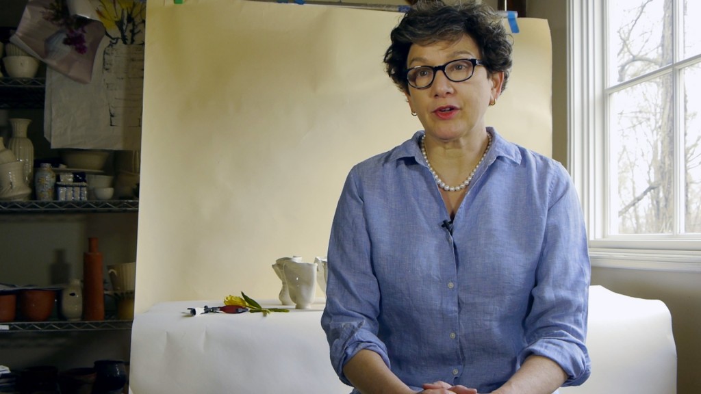A woman wearing glasses looks at the camera.