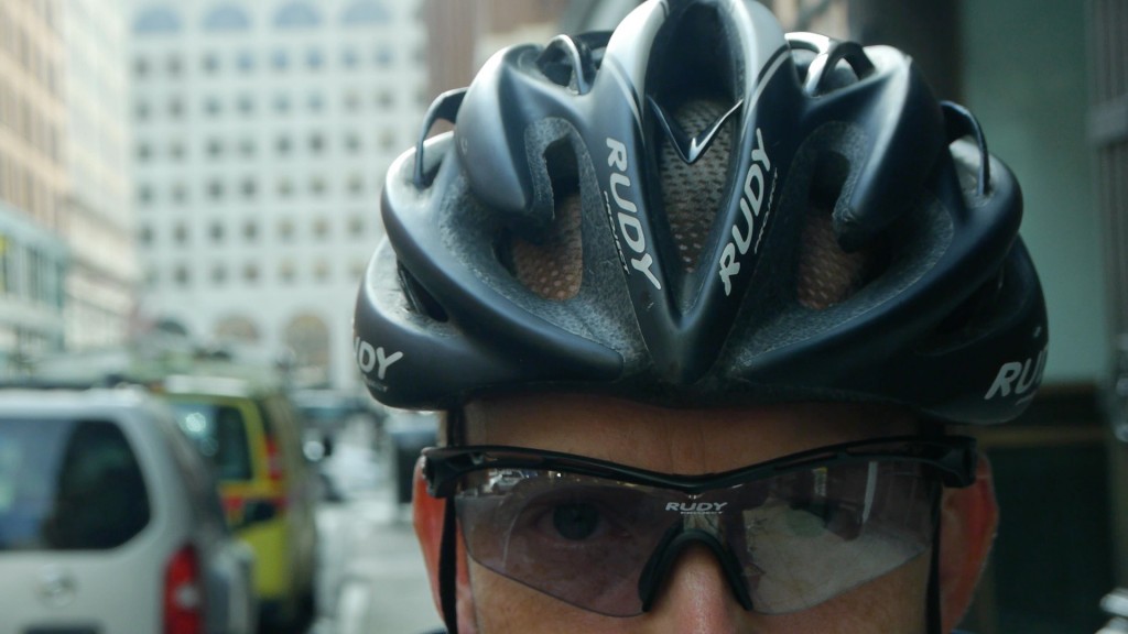 Closeup of a man wearing a bike helmet and sunglasses.