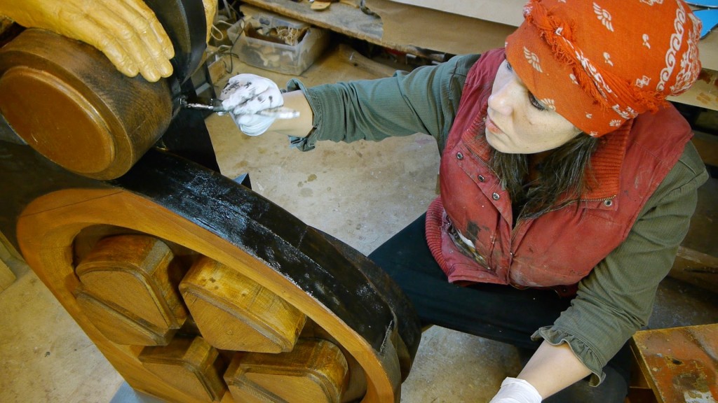 An artist paints wooden sculpture.