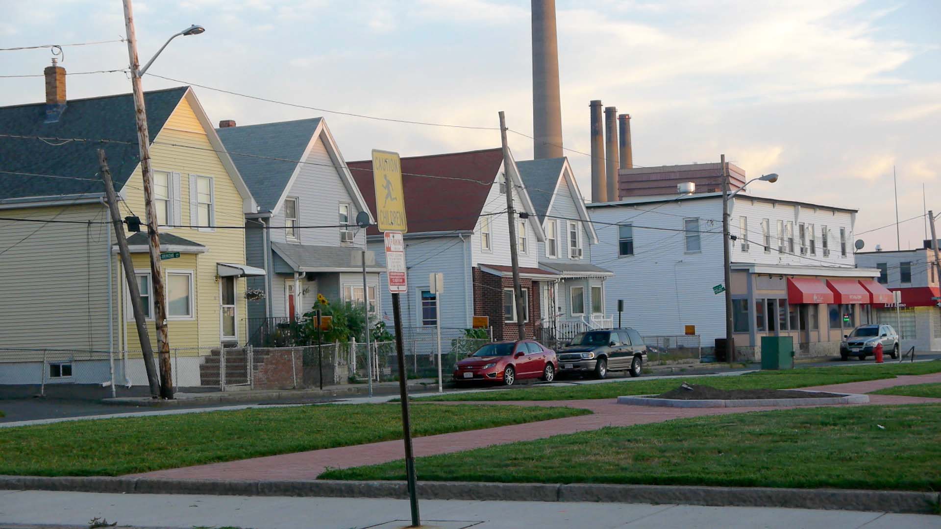A row of houses with smokestacks towering over them.