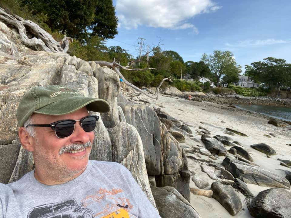 Mark sitting on a rock on a beach in Maine.