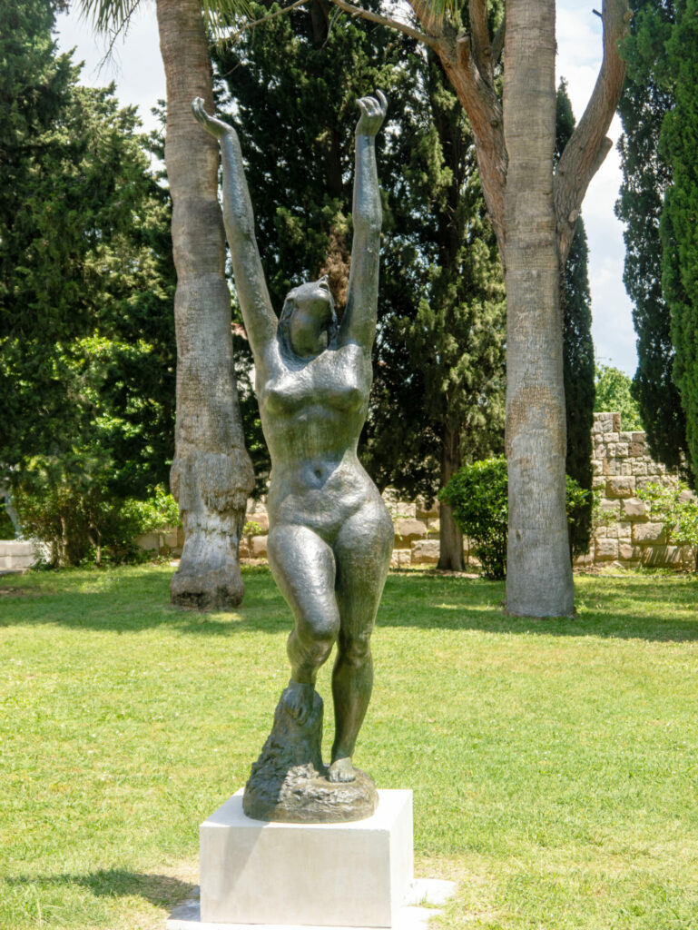 A statue of a naked woman with her arms reaching to the sky.