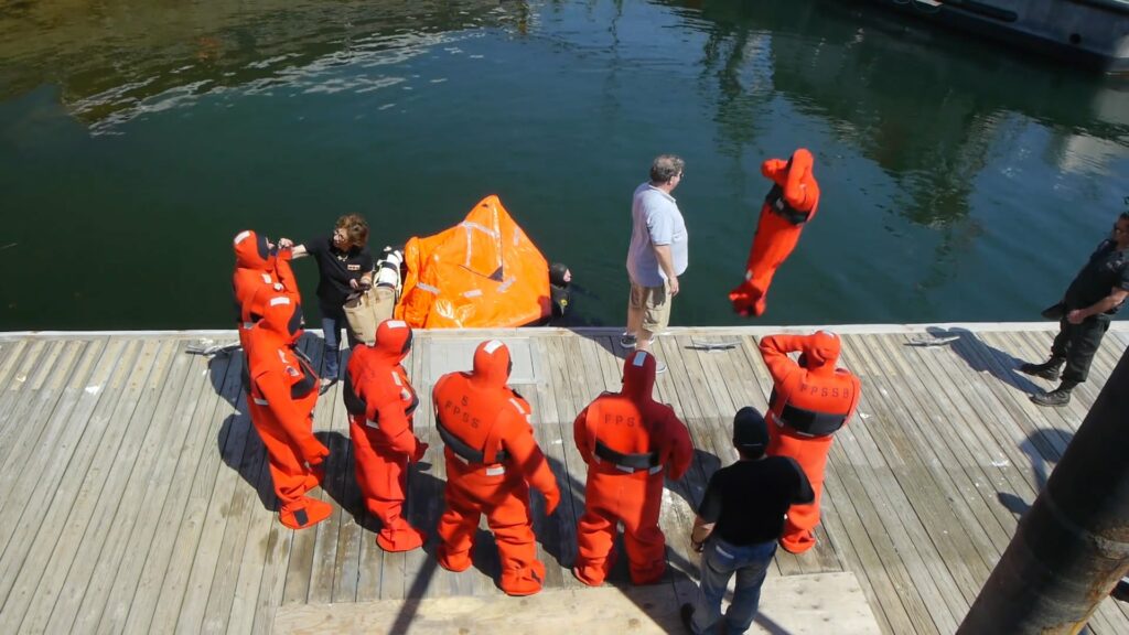 Men in orange safety gear jumping into the water.