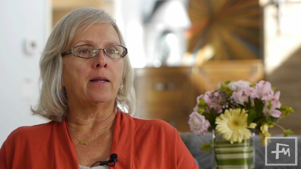 Woman wearing glasses and an orange shirt.