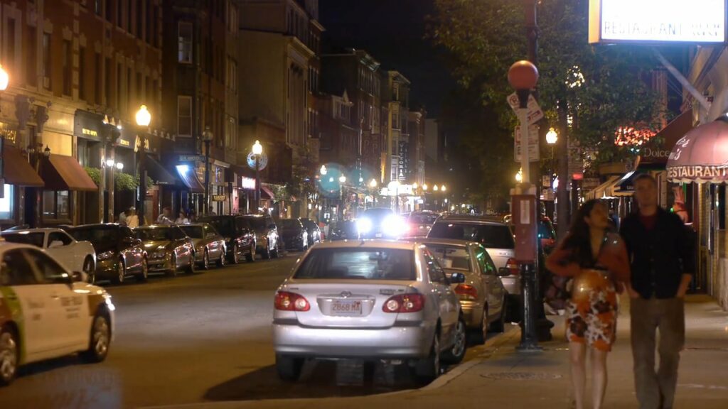 A couple walks down a street at night in Boston's North End neighborhood.