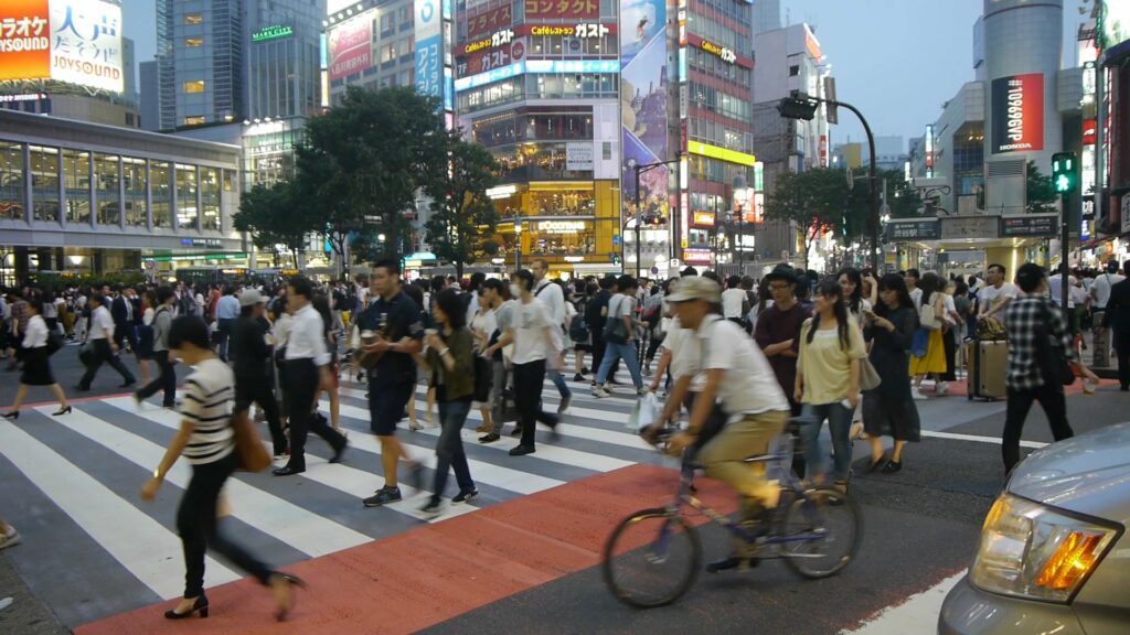 Numerous pedestrians cross a busy intersection in Tokyo.