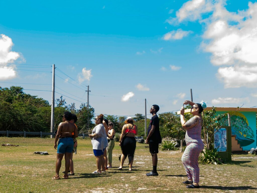 People lined up and looking in one direction under the hot sun.